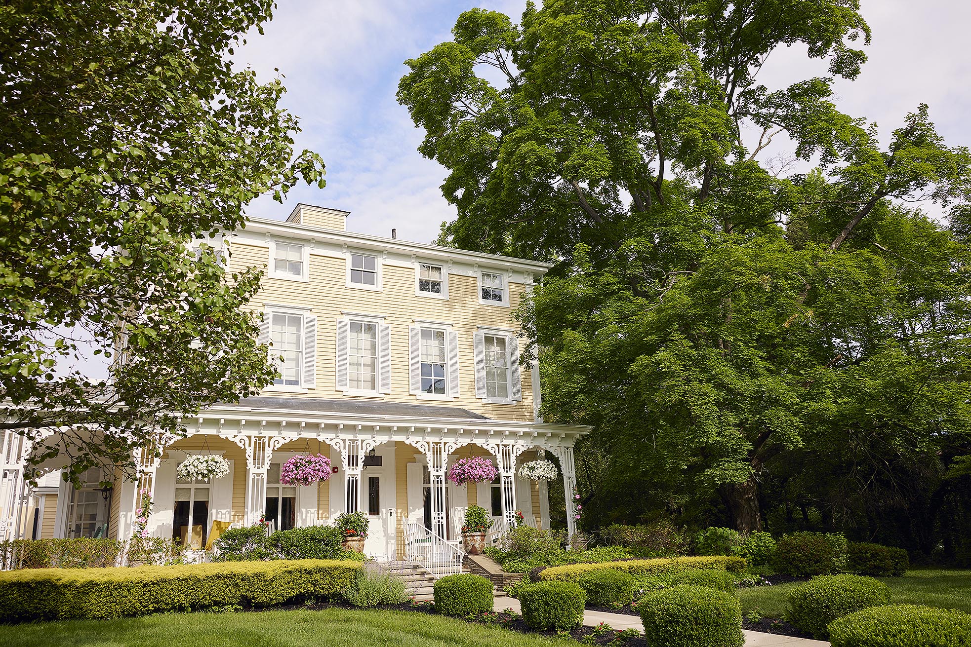 A stately residence with hanging baskets overflowing with summer flowers